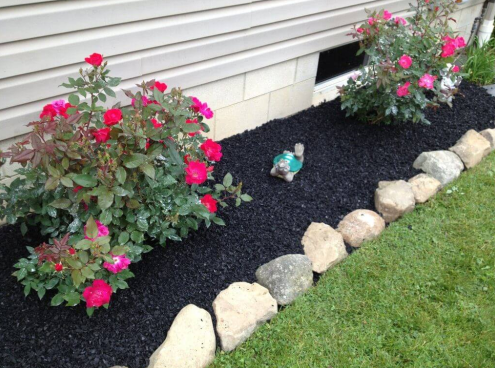 Professional mulching with stone edging and flowering plants demonstrating quality craftsmanship